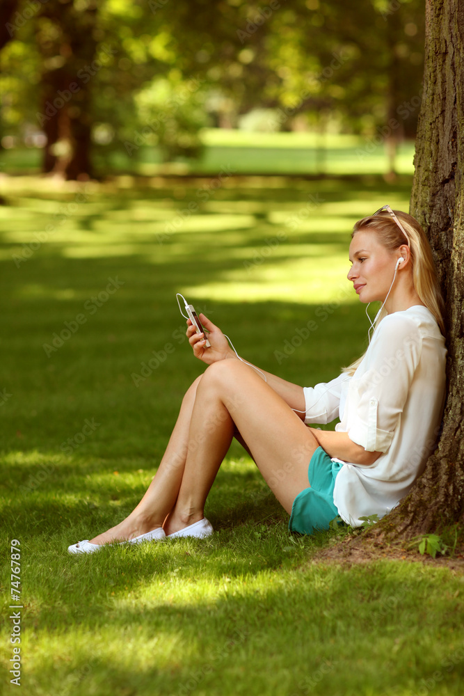 Young woman with smart phone in a park Young woman with smart phone in a park
