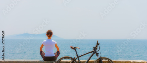 Cycling - Biker girl sitting at seaside, woman fitness