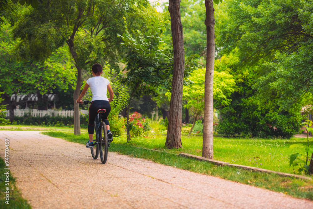 Cycling outdoor - Biker girl exercise in the park, woman fitness Cycling outdoor - Biker girl exercise in the park, woman fitness