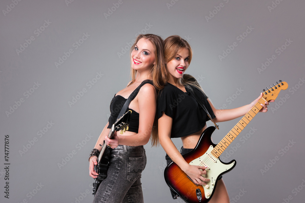 Two beautiful girls playing guitars