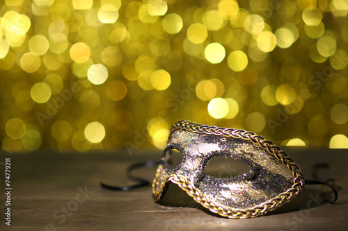 Beautiful carnival mask on table on golden background
