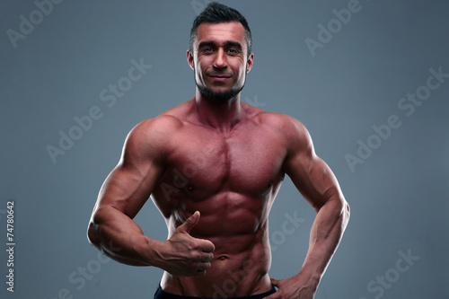 Happy muscular man showing thumb up