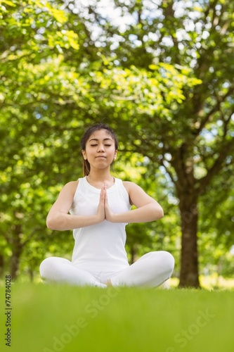 Healthy woman sitting with joined hands at park