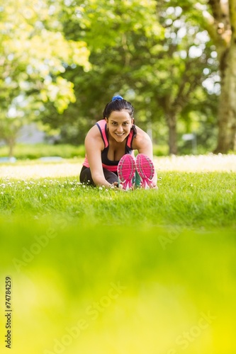 Fit brunette warming up on the grass