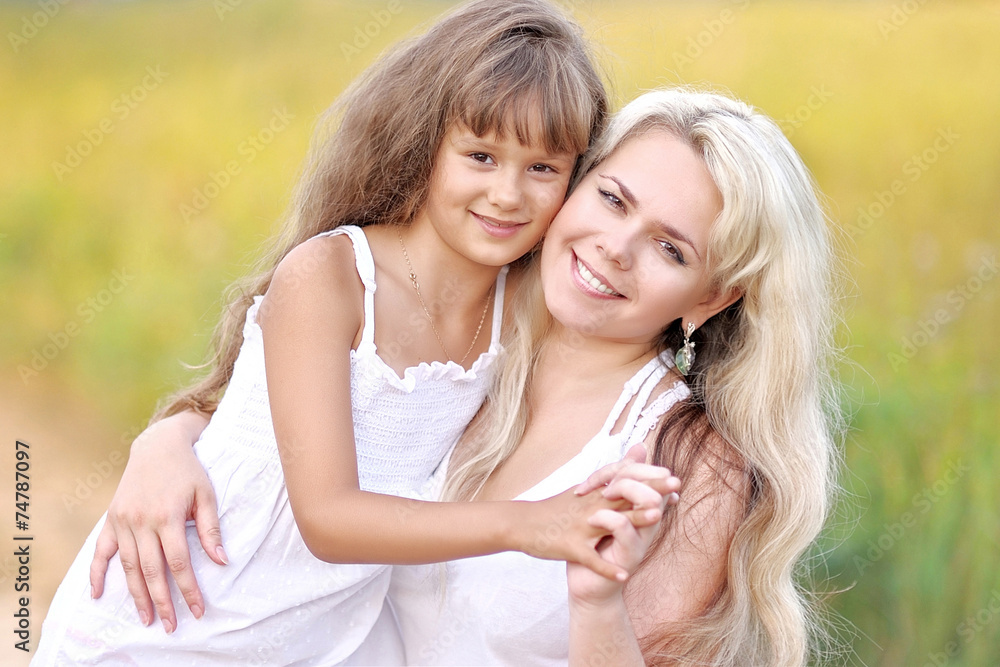 Young mother hugging her daughter in summer nature