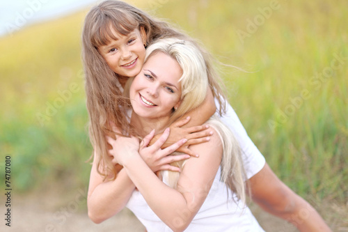 Young mother hugging her daughter in summer nature