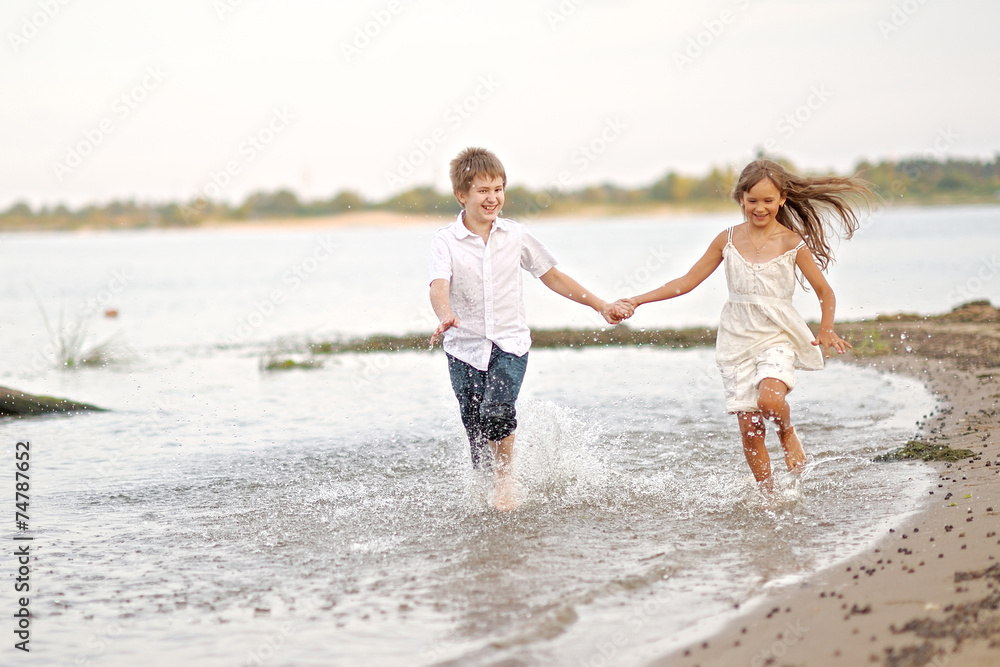 Portrait of a boy and a girl running on the beach Portrait of a boy and a girl running on the beach