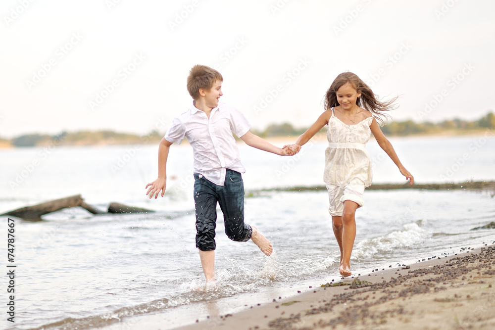 Portrait of a boy and a girl running on the beach Portrait of a boy and a girl running on the beach
