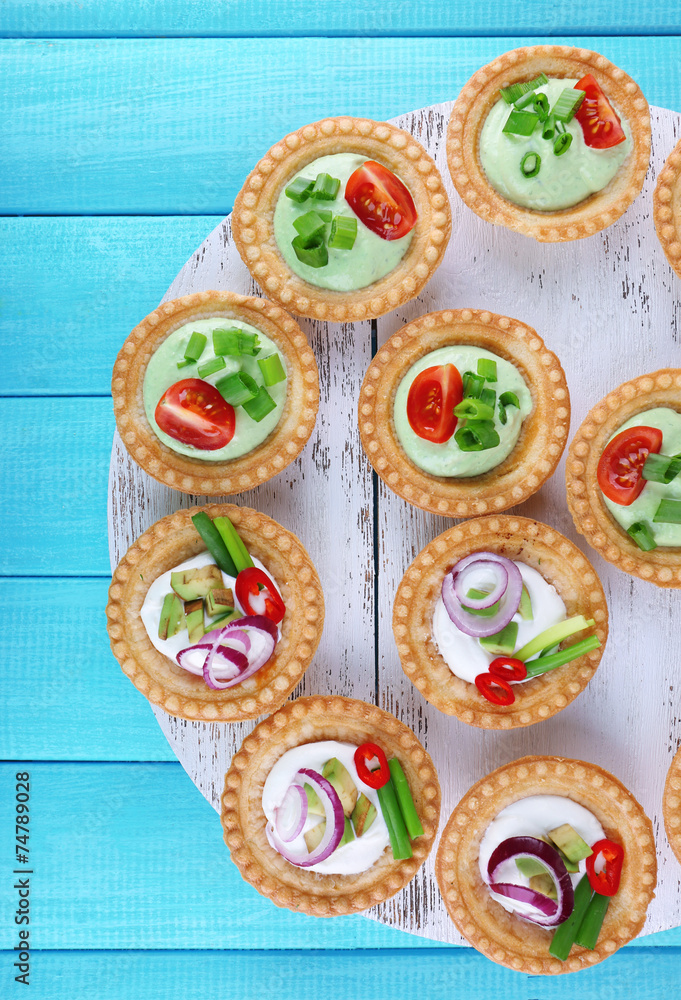 Fototapeta premium Tartlets with greens and vegetables with sauce on tray on table