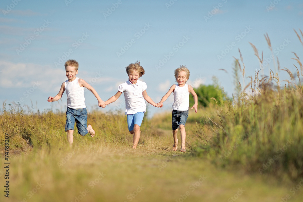 three children playing on meadow in summer three children playing on meadow in summer
