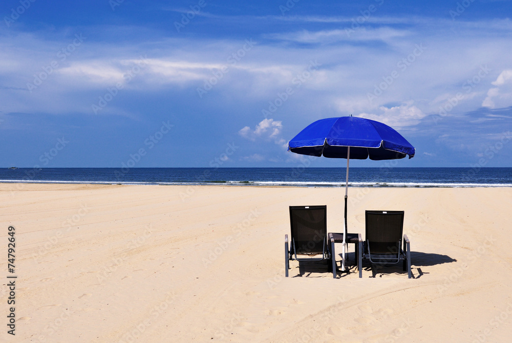 Beach chairs and blue umbrella on a sand beach