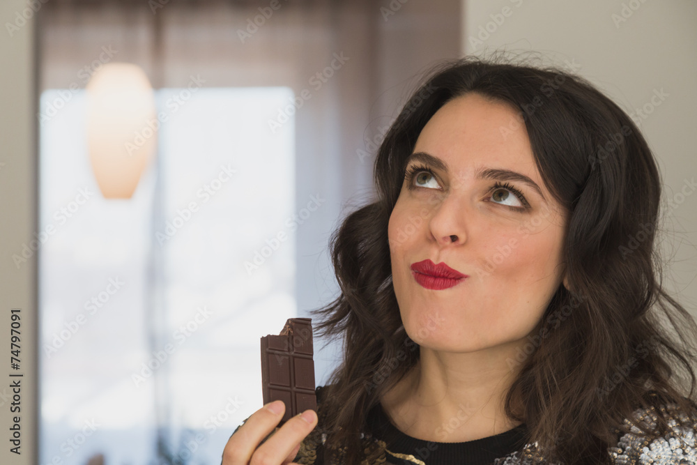 Beautiful young brunette with long hair eating chocolate Beautiful young brunette with long hair eating chocolate