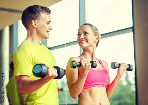smiling man and woman with dumbbells in gym © Syda Productions