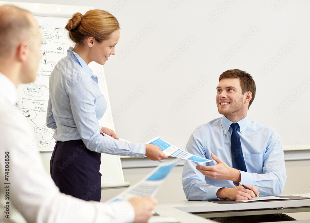 Obraz premium smiling woman giving papers to man in office