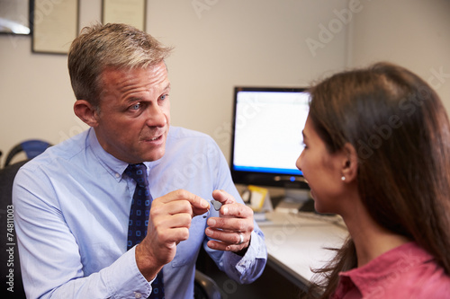 Doctor Fitting Female Patient With Hearing Aid photo