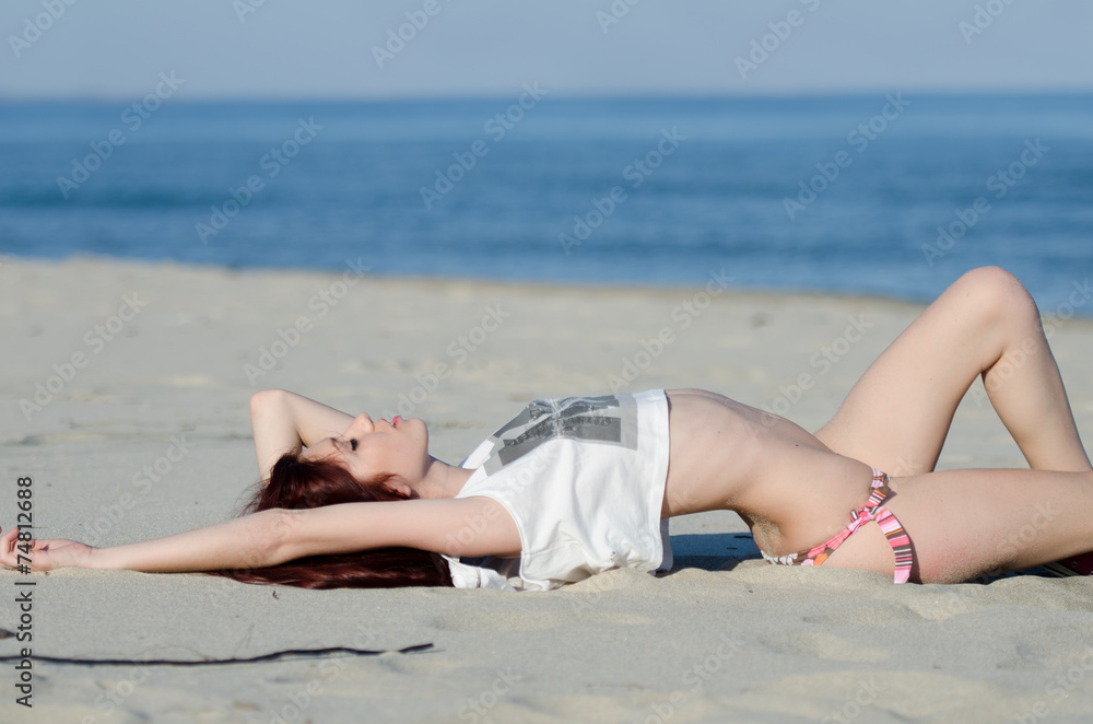 Sexy woman wearing a bikini and white shirt on a sand beach Sexy woman wearing a bikini and white shirt on a sand beach