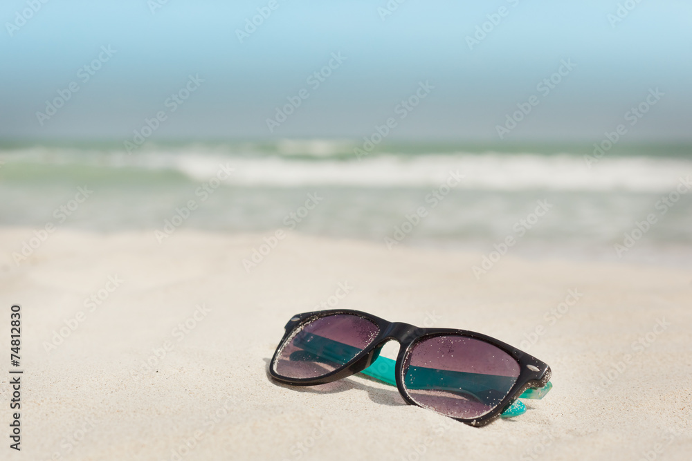 Sunglasses in the sand on the seashore. vacation time