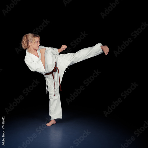 Young Karate Woman in a White Kimono Kicking