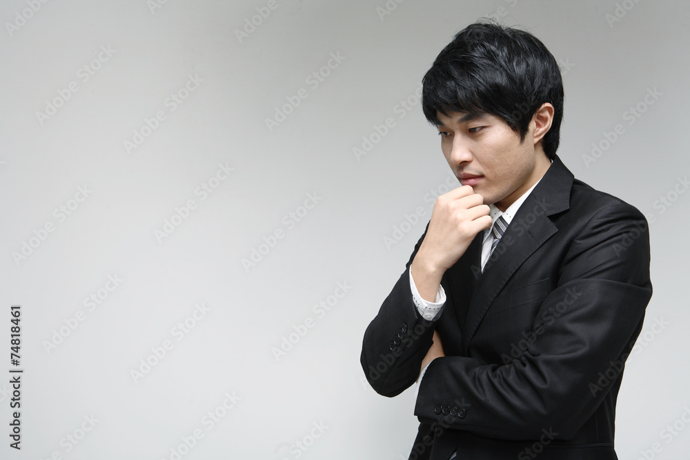 흰 배경 스튜디오에서 검은 정장을 입고 미소를 지으며 제스처를 취하는 젊은 남성 