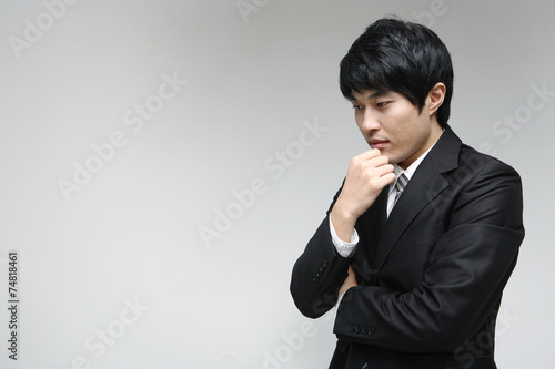 흰 배경 스튜디오에서 검은 정장을 입고 미소를 지으며 제스처를 취하는 젊은 남성 