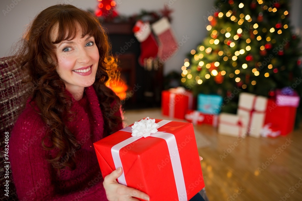 Happy redhead holding a gift at christmas Happy redhead holding a gift at christmas