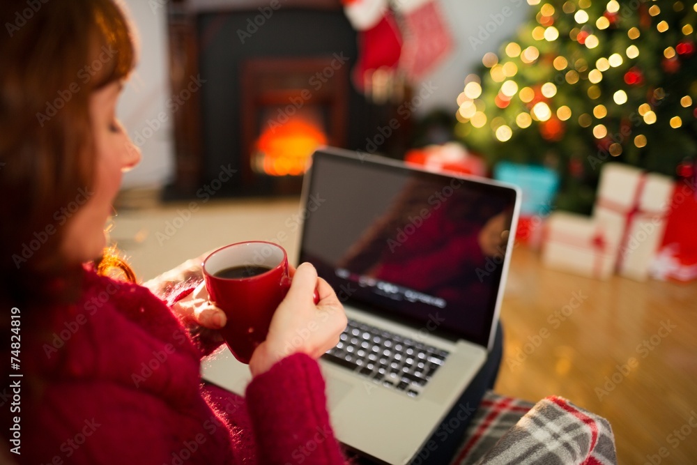 Redhead holding hot drink and using laptop Redhead holding hot drink and using laptop