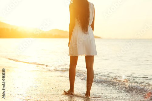 Beautiful girl walking on the beach at sunset, freedom concept