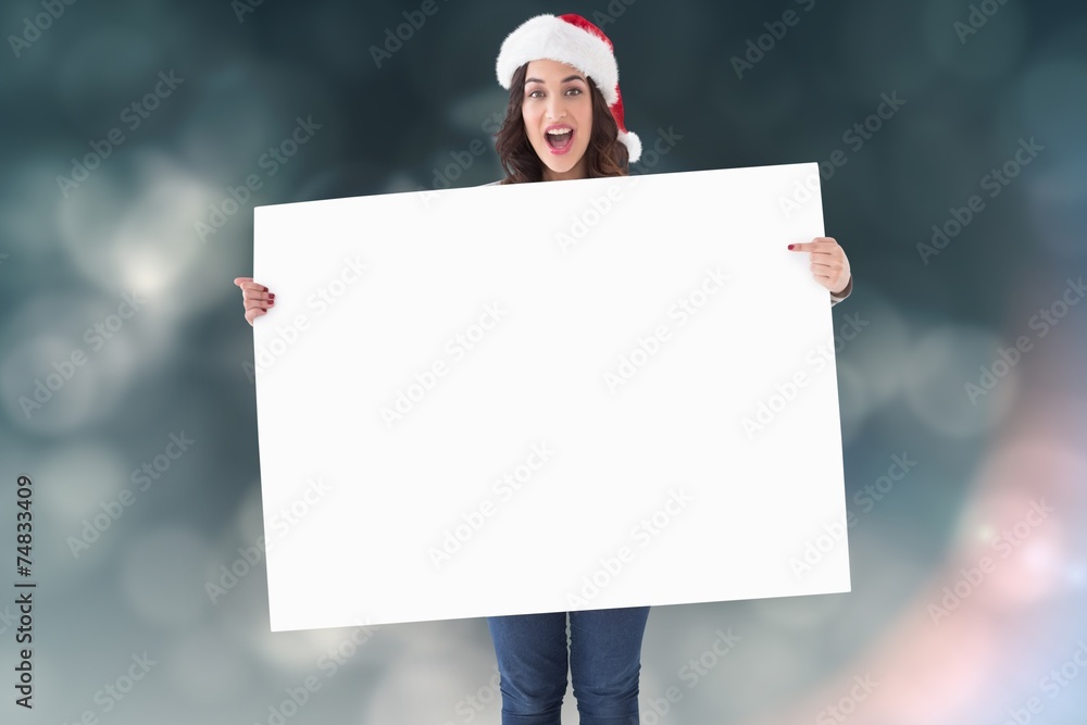 Pretty brunette in santa hat pointing white poster Pretty brunette in santa hat pointing white poster