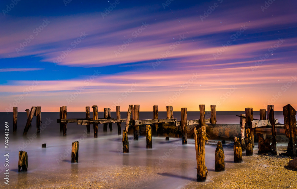 Obraz premium Ruins of an old pier on Sunset Beach at night, in Cape May, New