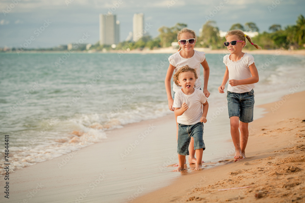 Three happy children running on the beach