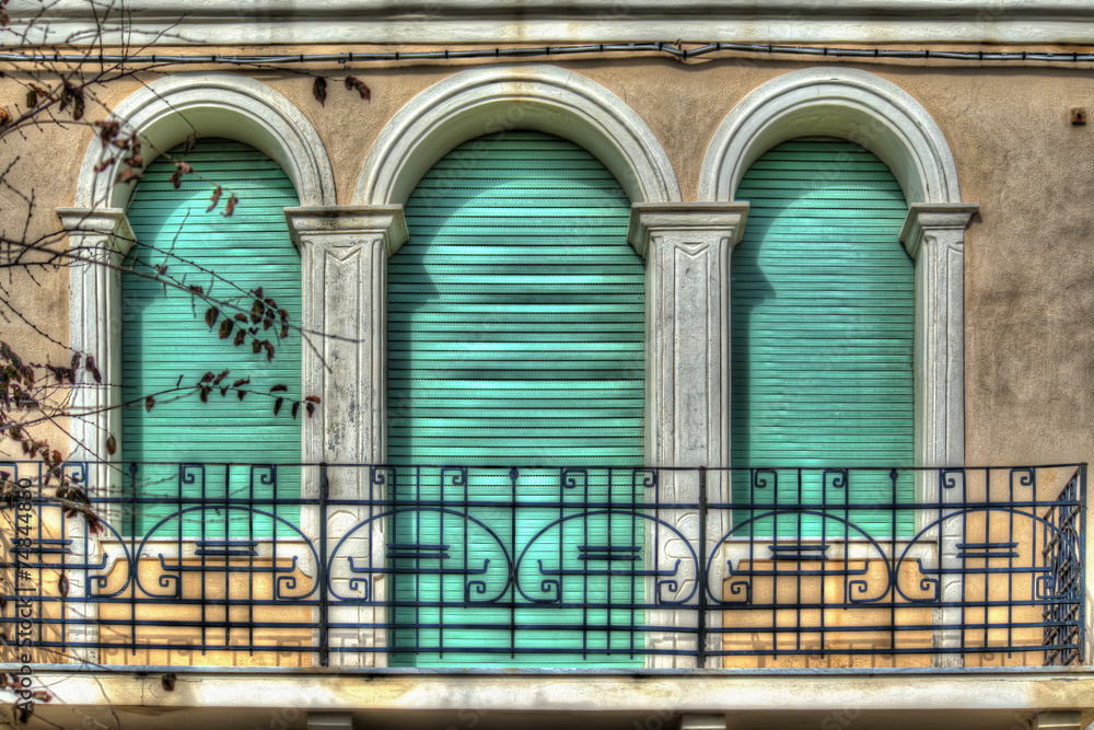 three green roller blinds in an old italian balcony three green roller blinds in an old italian balcony