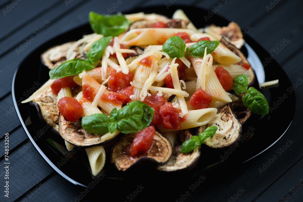 Pasta alla Norma on a black glass plate, horizontal shot