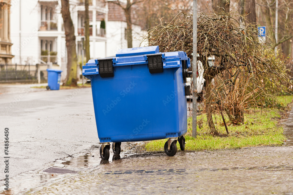 Ein blauer Müllcontainer aus Kunststoff steht am Strassenrand Ein blauer Müllcontainer aus Kunststoff steht am Strassenrand