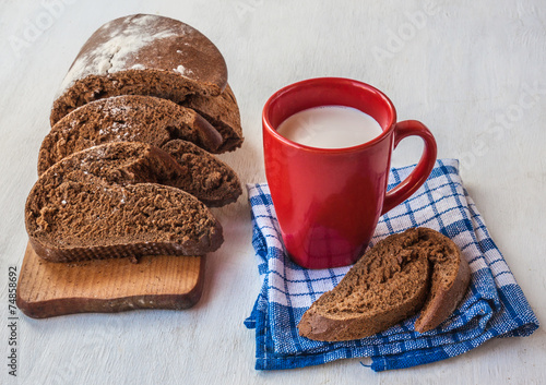 Sliced rye bread Tabatiere on a cutting board and  red cup with photo