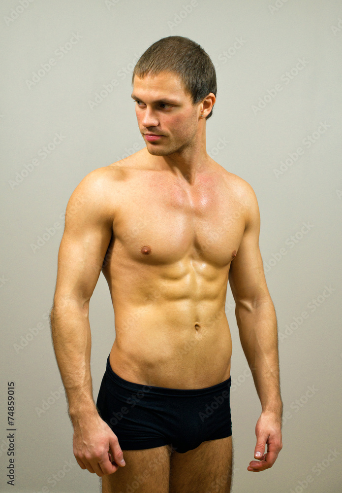 Muscular male model posing on grey background.