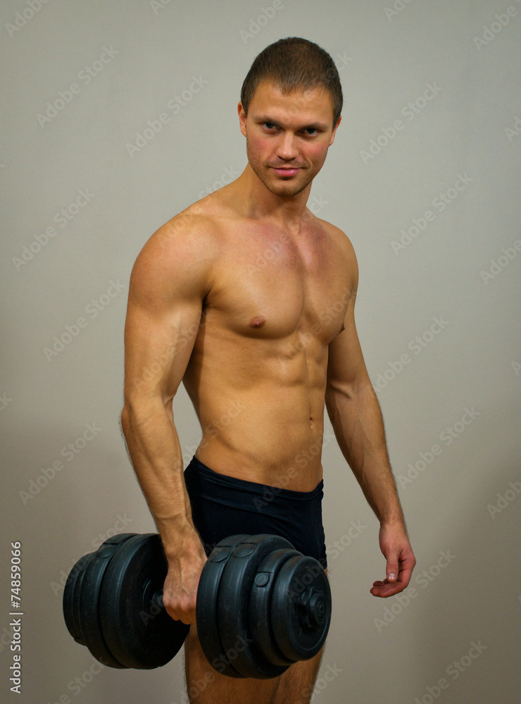 Handsome muscular male model with dumbbell.