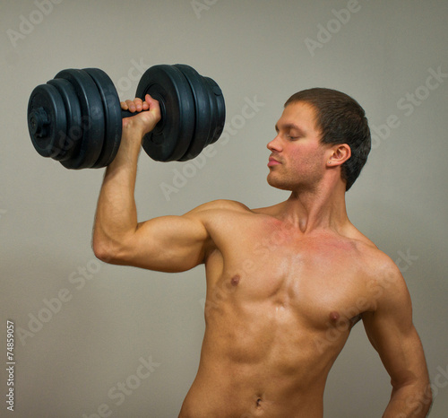 Handsome muscular male model with dumbbell.