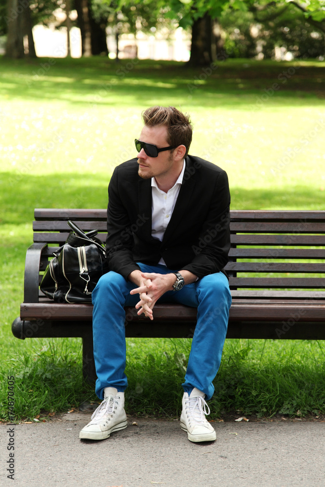 Obraz premium Man sitting down on a bench
