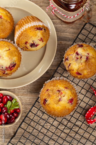 Muffins with cranberry on cooling rack on wooden background.