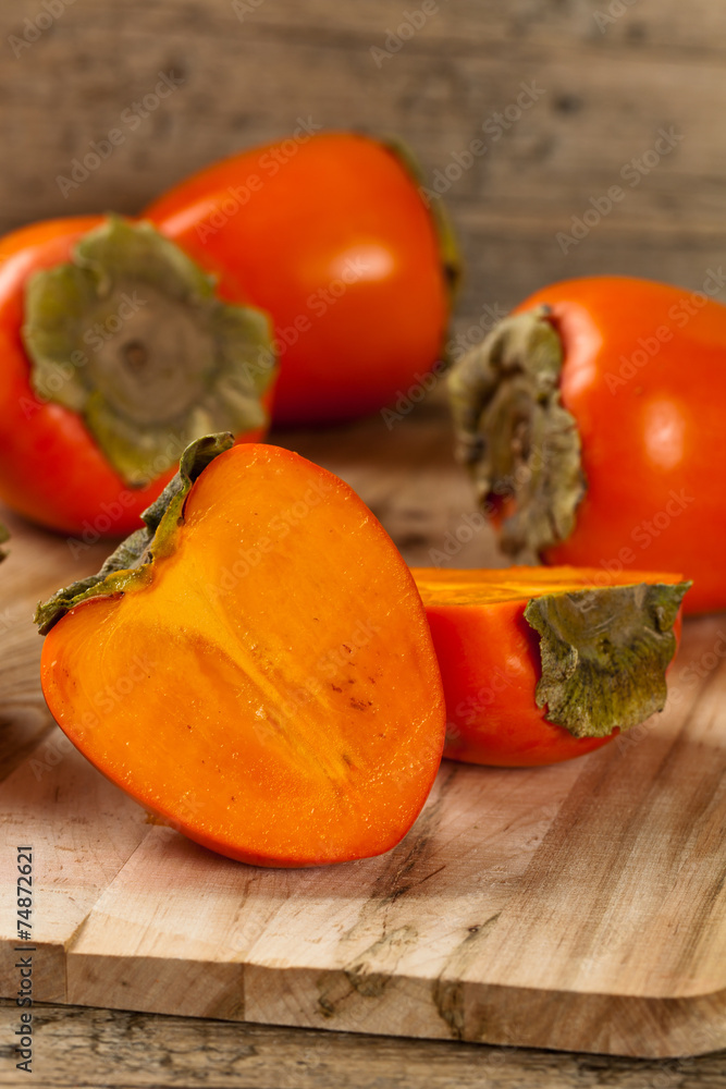 Delicious orange persimmons on wooden table. Selective focus. Delicious orange persimmons on wooden table. Selective focus.