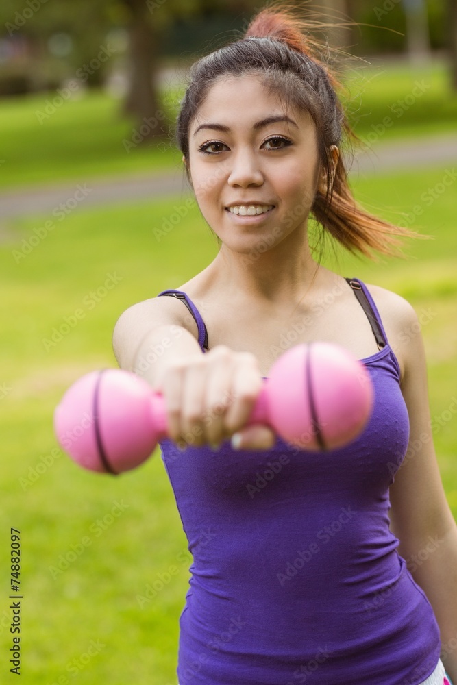 Fototapeta premium Healthy woman lifting dumbbell in park