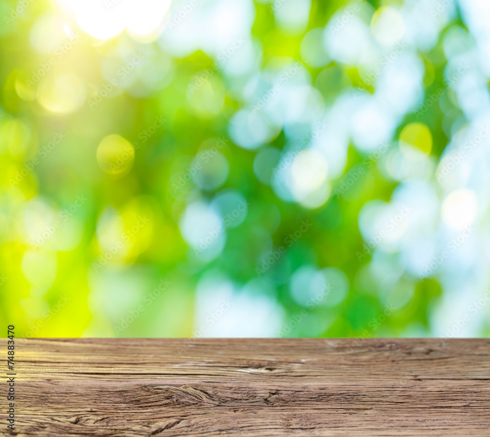 Old wooden table with green foliage on the background.