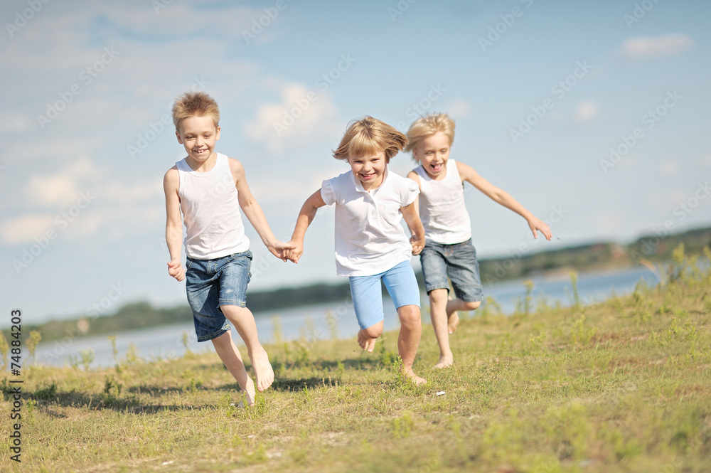 Fototapeta premium three children playing on meadow in summer