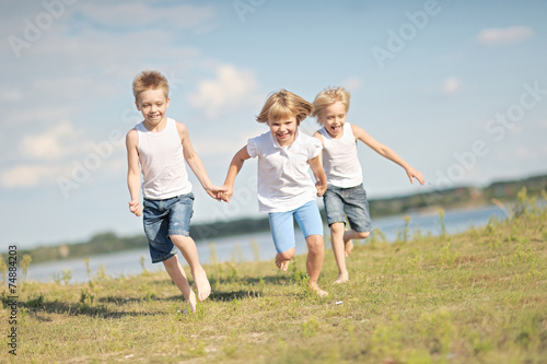 three children playing on meadow in summer