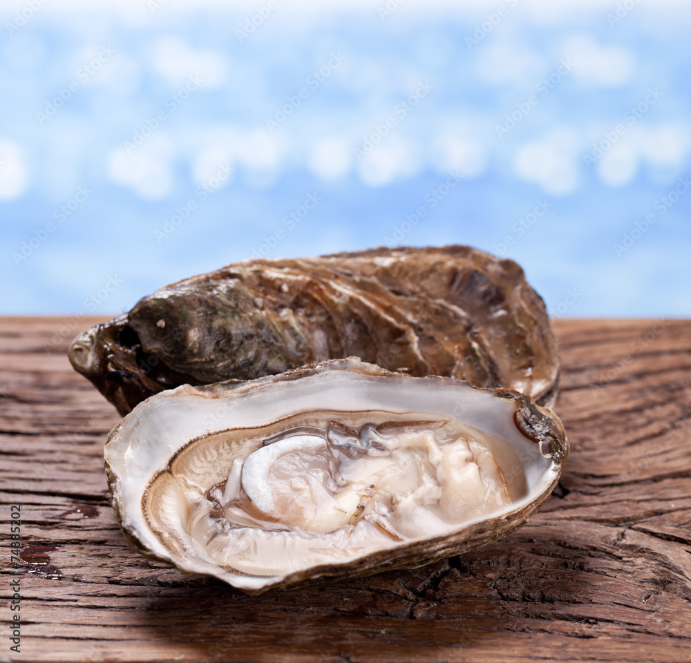 Raw oyster on wood. Sea at the background.