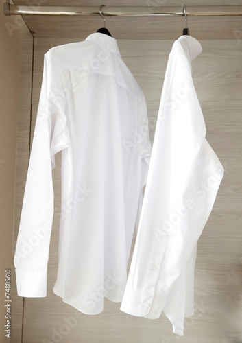 white shirts hanging on rack in built-in cupboard