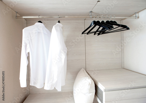 white shirts hanging on built-in cloths racks, with drawers and