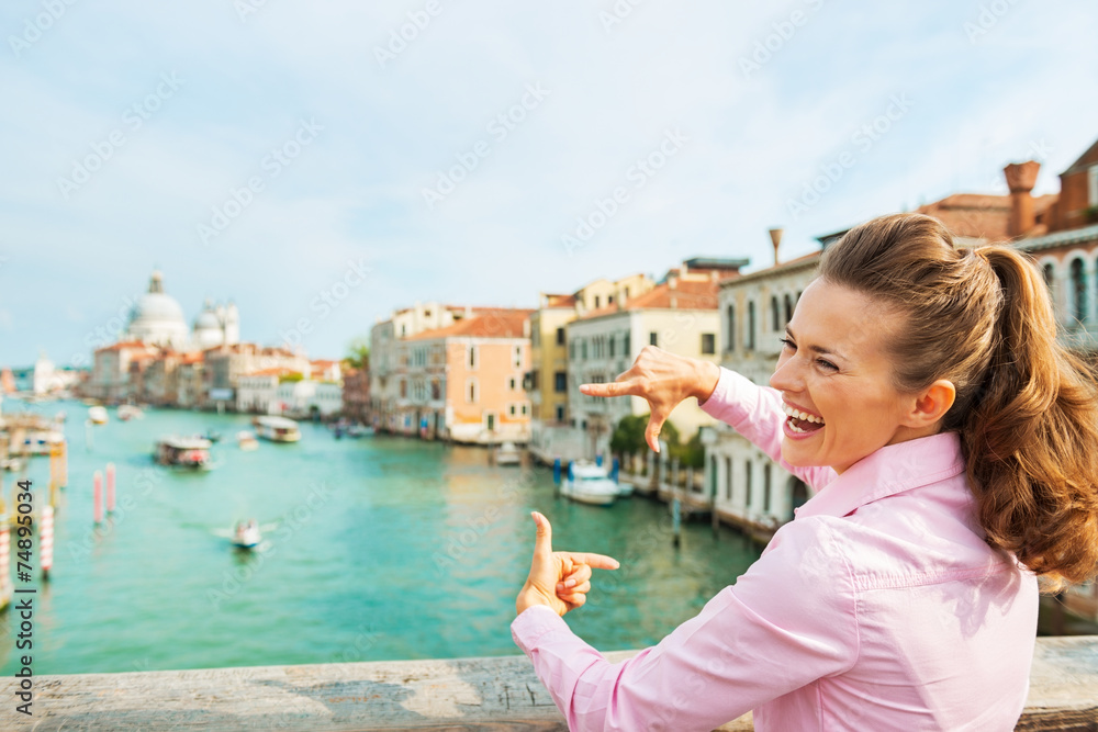 Girl framing with hands while standing on bridge in venice