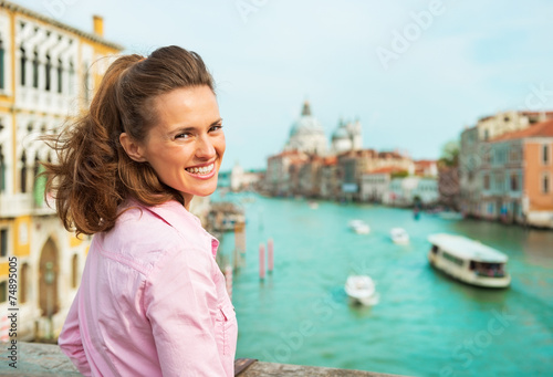 Happy woman standing on bridge with grand canal in venice
