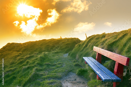 bench on a cliff edge with sunset photo